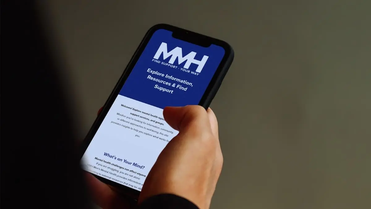 Person browsing the MMH Men’s Mental Health website on a smartphone to find support and resources.