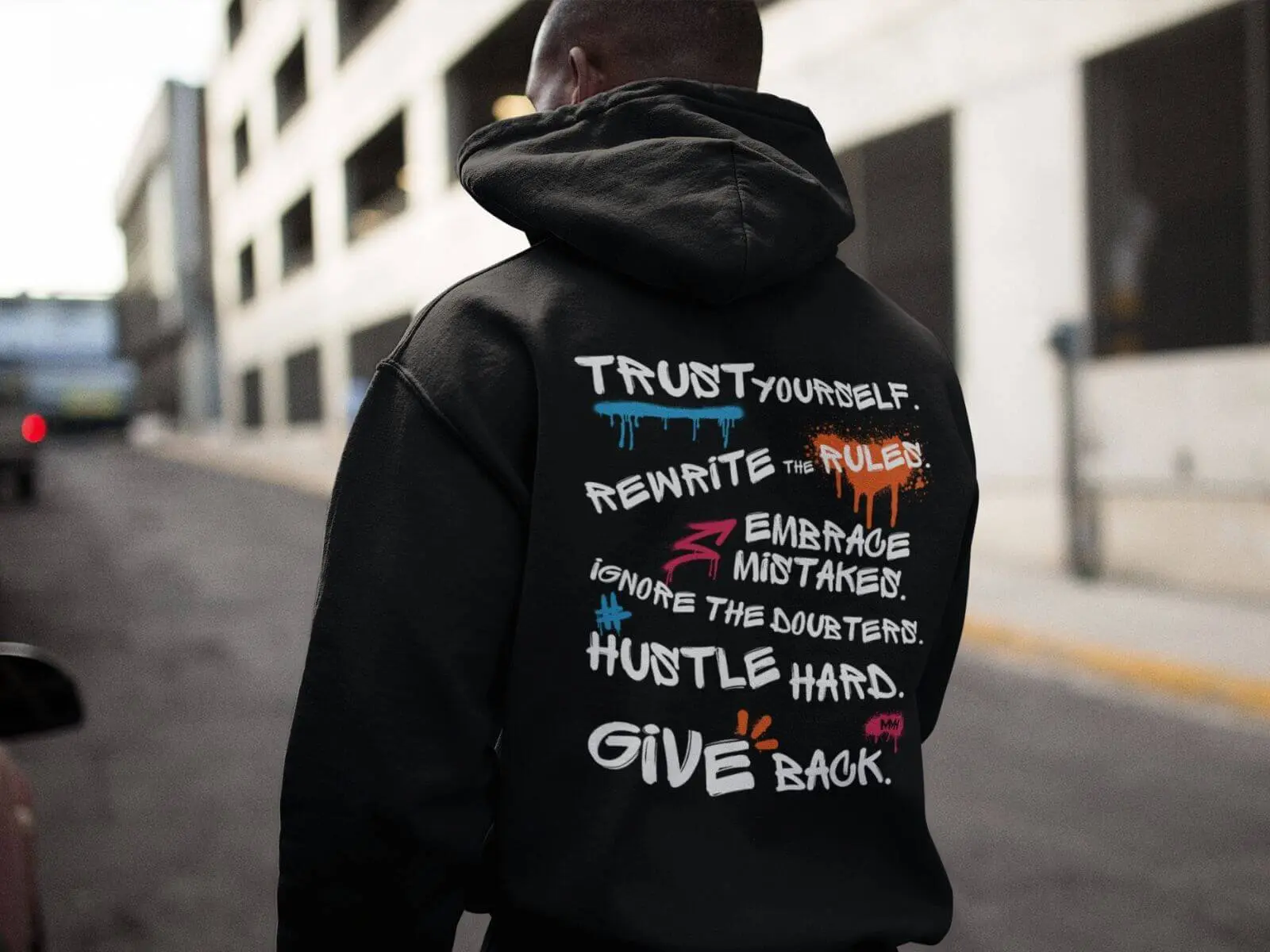 Person wearing a black Rules for Life hoodie with bold back print featuring motivational statements like trust yourself and give back.